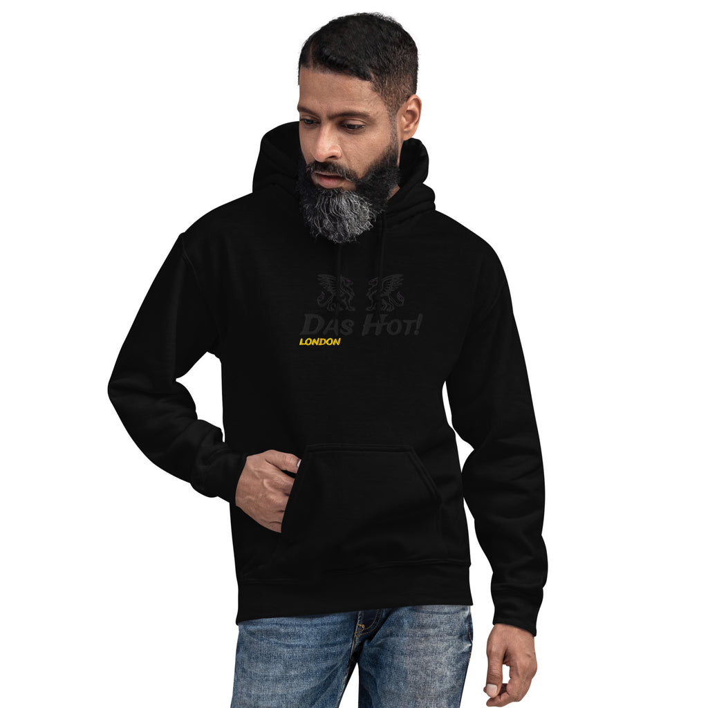 Front crop view of a bearded male model wearing the premium black unisex streetwear hoodie by Das Hot! London. The design highlights the high-density black-on-black raised embroidery of the twin heraldic griffins and the Das Hot! brand name across the chest, contrasted by a bright yellow-gold embroidered London accent located directly below the brand name.