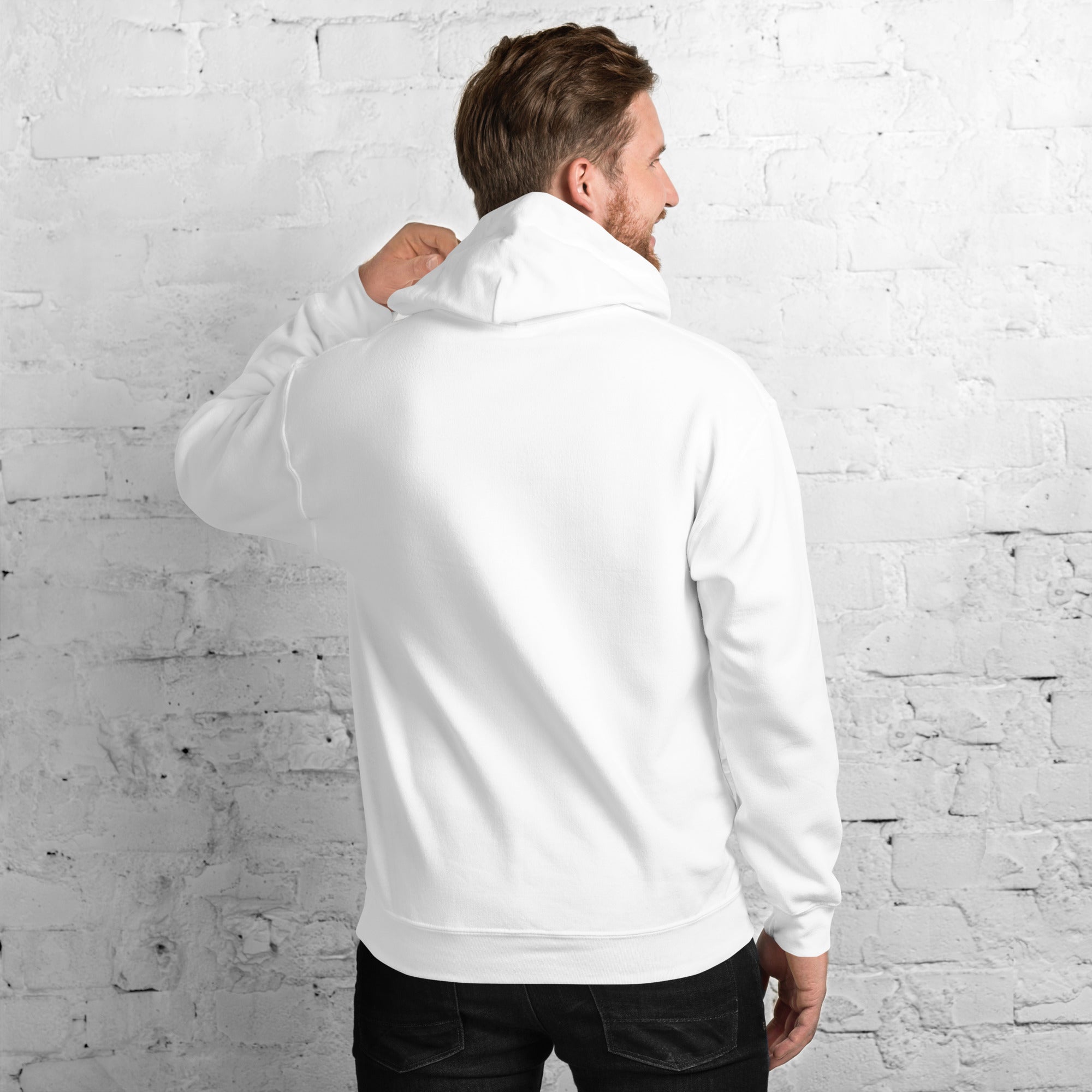 Rear view of a male model standing against a white brick wall, showcasing the clean back profile and fit of the premium white unisex streetwear hoodie by Das Hot! London.