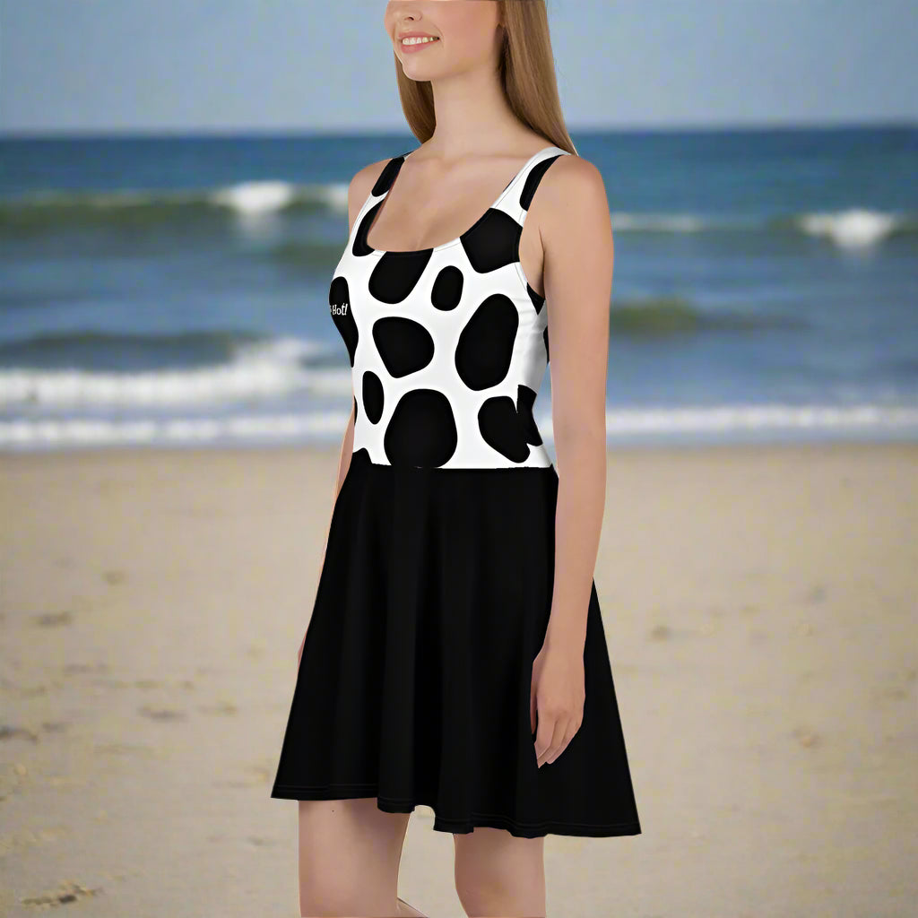 Woman wearing a black and white polka dot dress at the beach with sand and waves