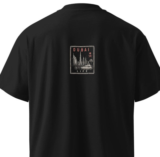 Back of a black Das Hot! oversized streetwear T-shirt featuring the Das Hot! Passport™ Dubai Life collectible badge with the Dubai skyline, luxury yacht, Burj Al Arab, Burj Khalifa, and UAE-inspired artwork.