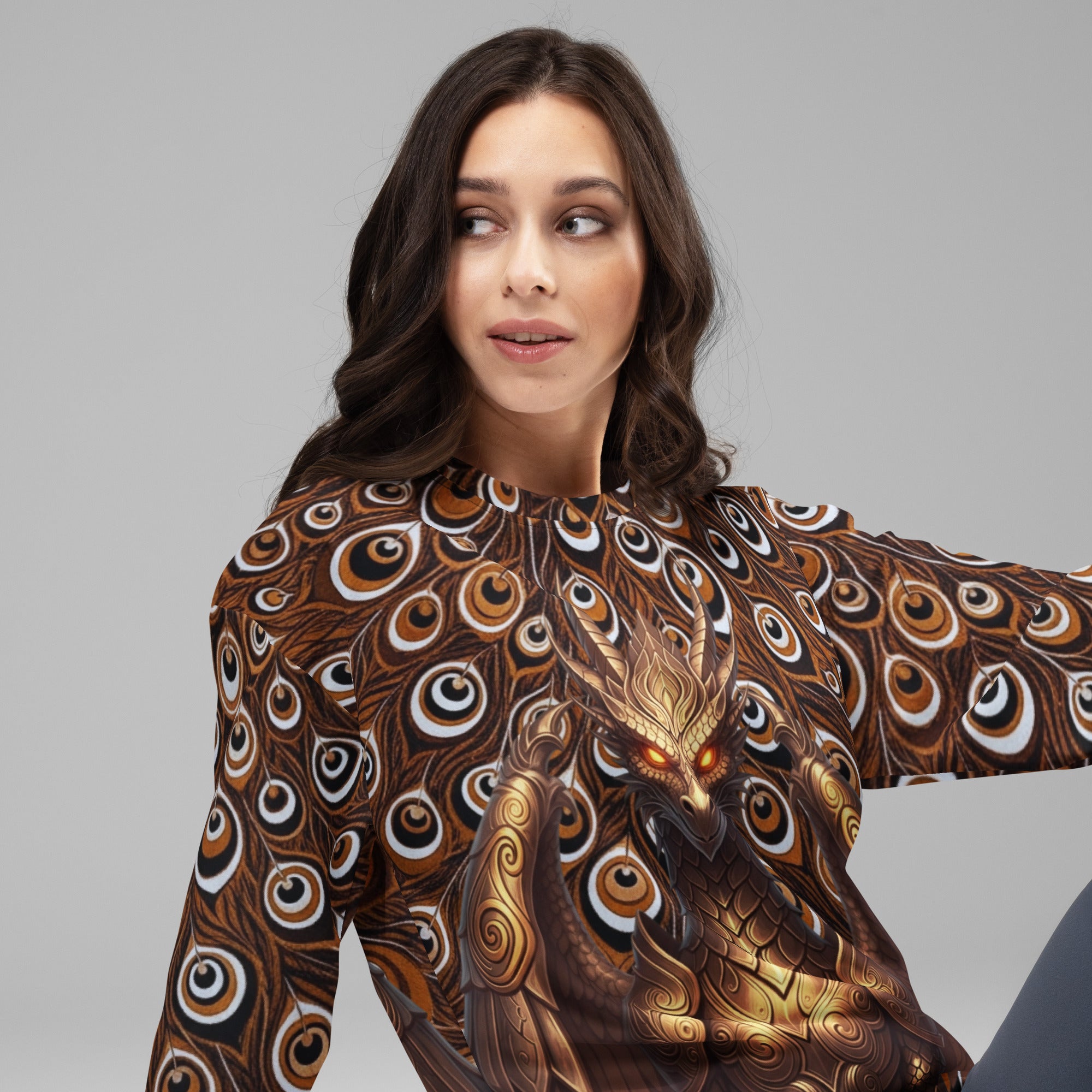 Female model wearing the Dragon Thousand Eyes unisex long-sleeve crewneck, featuring a metallic gold dragon design over a dark brown and black peacock feather print.