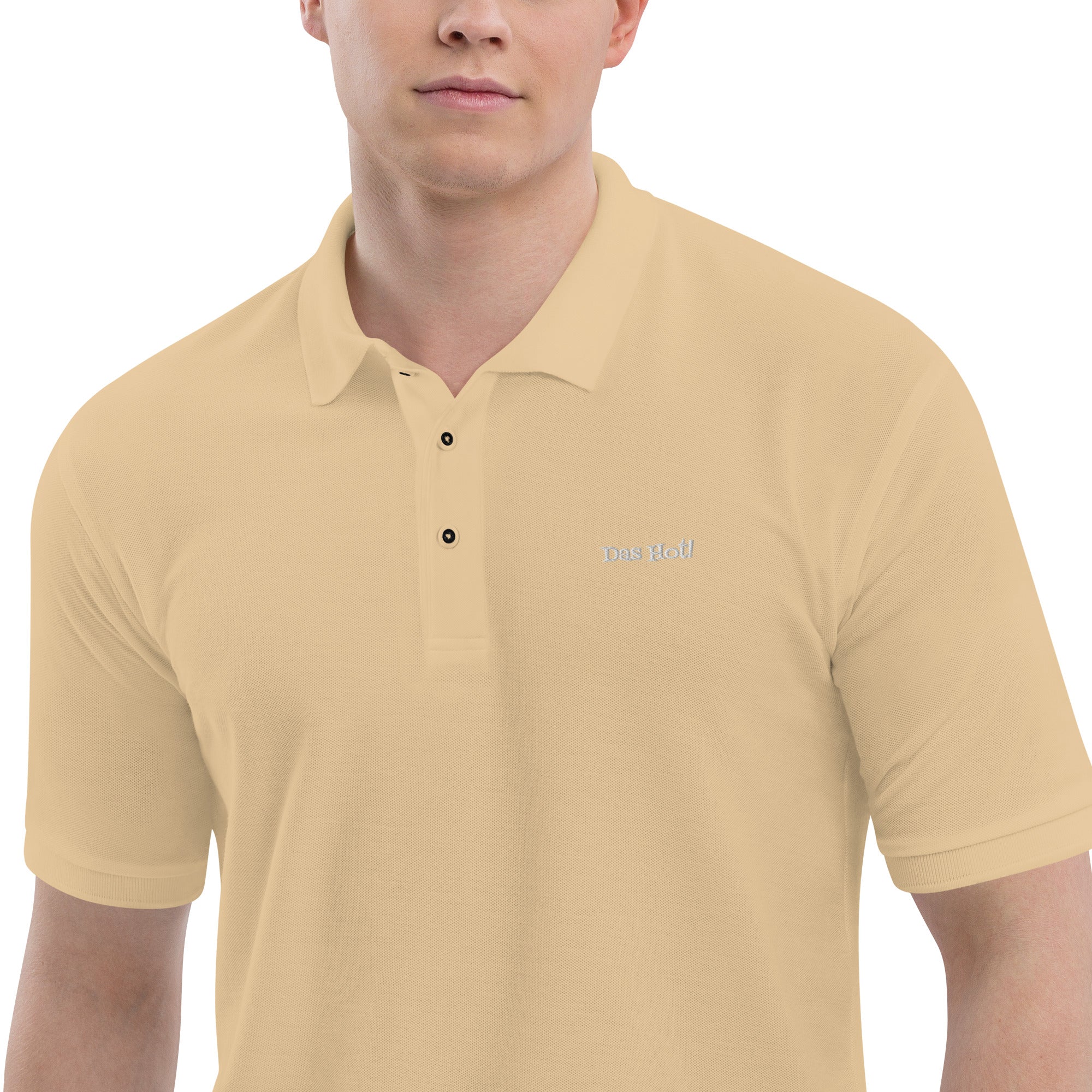 Man wearing a beige polo shirt with a logo on a white background
