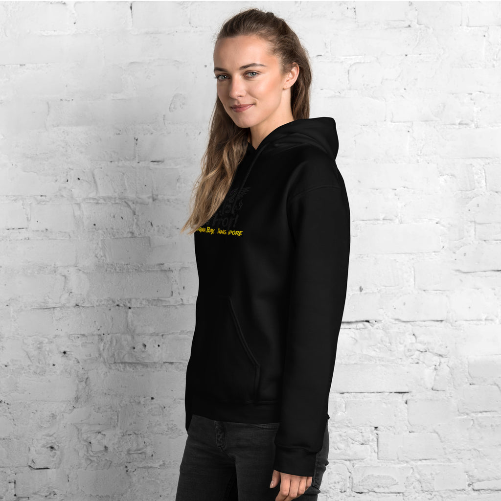 Person wearing a black hoodie with yellow text against a white brick wall