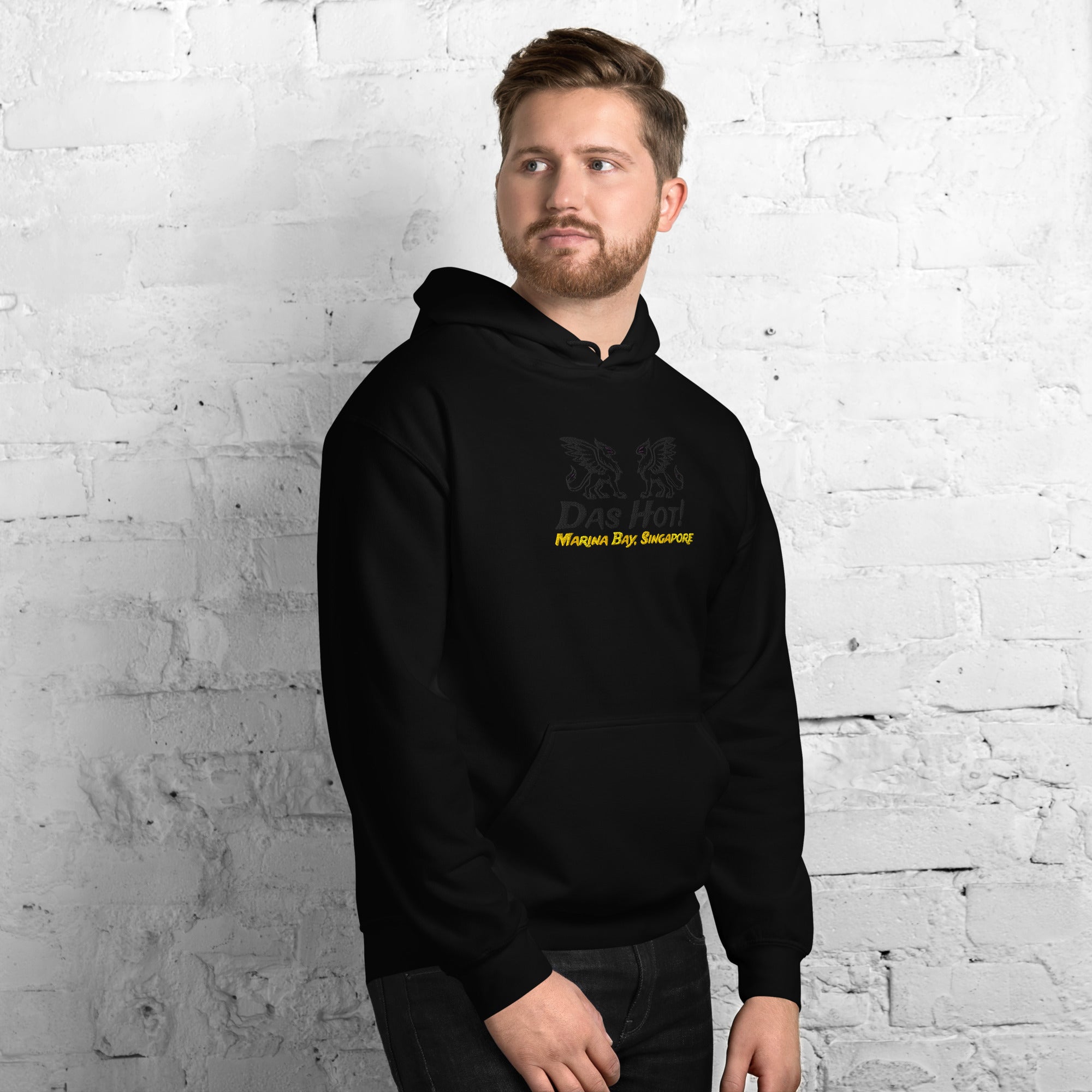 Man wearing a black hoodie with yellow text against a white brick wall